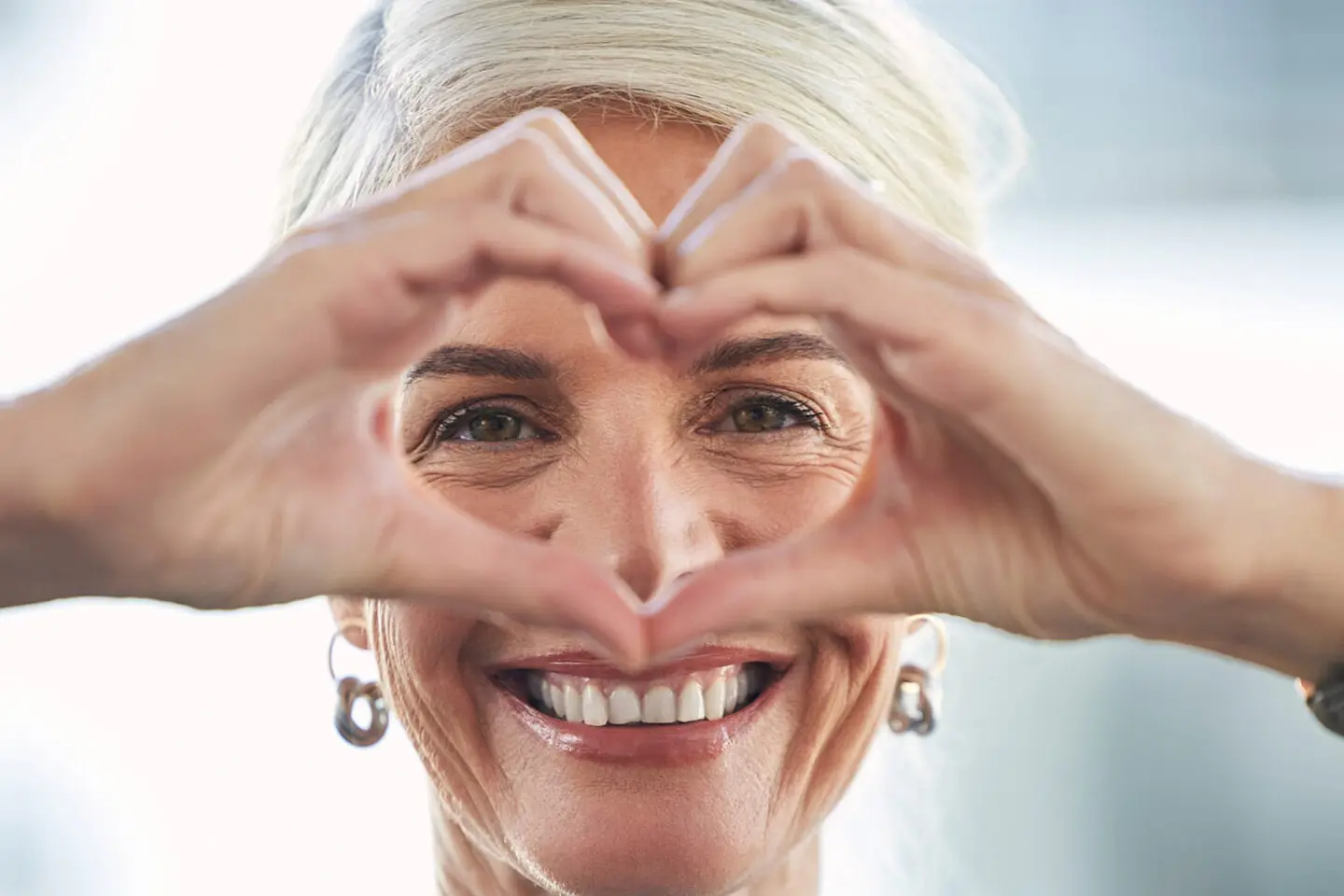 A woman making a heart with her hands.