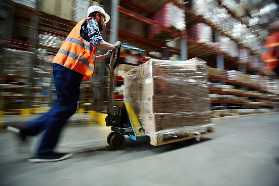 A man pushing a cart in a warehouse.