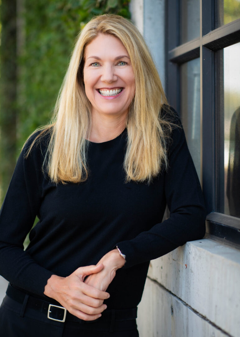 A woman in black shirt standing next to a window.